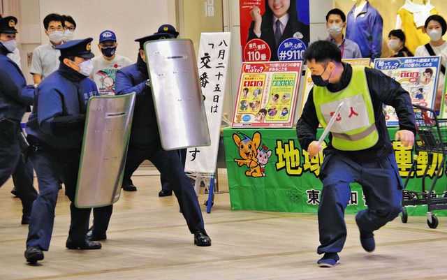 訓練で、刃物に模した棒を手に暴れる不審者役（右）と取り押さえようとする警察官＝いずれも武蔵村山市で