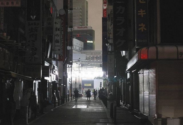 地震の影響で停電し、明かりが消えた東京・新橋の飲食店街。奥はＪＲ新橋駅＝１７日午前１時すぎ
