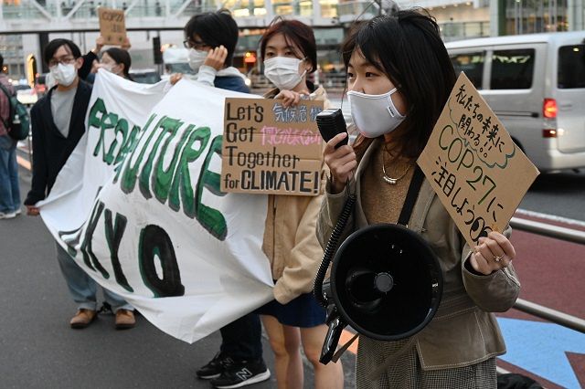 COP27への注目を呼び掛けるプラカードを持ち、気候変動への危機感を語る参加者＝東京・JR新宿駅前で