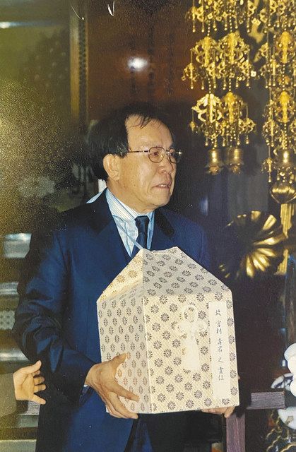 2006年、東京都目黒区の祐天寺で、父の名が記された遺骨の箱を抱える全承烈さん。遺骨は今も同寺にある＝本人提供