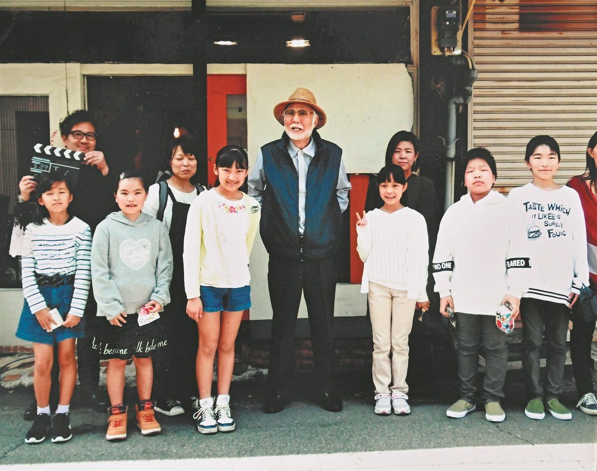 脚本、主演と監督も務めた映画「駄菓子屋小春」で子役らと記念撮影する八名信夫さん（中央）