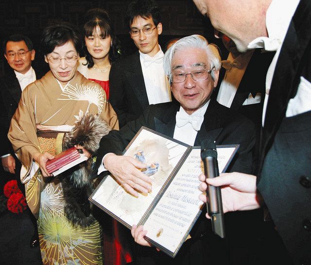 2008年12月、ノーベル賞の授賞式終了後、笑顔で取材を受ける益川敏英さん。左は妻の明子さん＝ストックホルム市内で