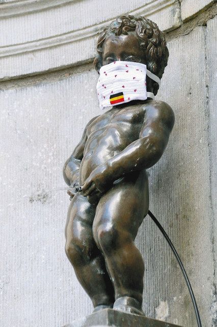 １１日、ベルギー・ブリュッセルで、国旗の描かれたマスクを着用する小便小僧（共同）