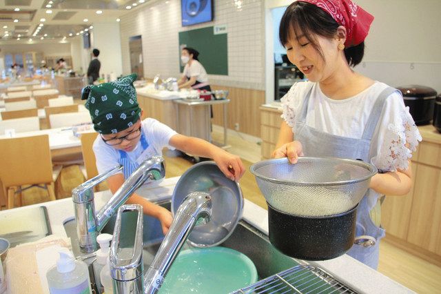 そうめんのゆで汁を洗い物のために再利用する親子＝名古屋市中区で