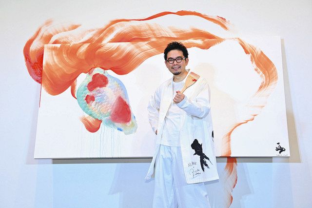 即興で仕上げたライブペインティングで描いた金魚の絵の前でポーズをとる深堀隆介さん＝１日、東京都台東区の上野の森美術館で