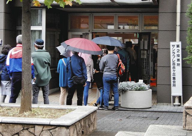 小雨が降る中、投票所への入場を待って並ぶ有権者たち ＝川崎市