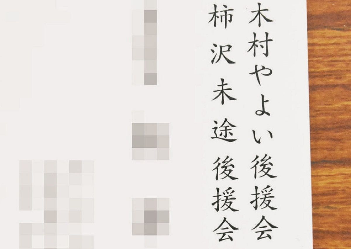 8月の有料広告を巡る木村氏の記者会見で、司会を務めた木村陣営の幹部が記者に差し出した名刺。木村、柿沢両氏の後援会の肩書きが並んでいる（一部画像処理）