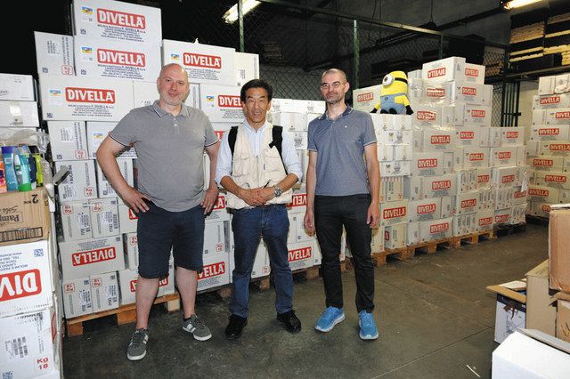 パスタなどの支援物資が山積みになったチーム・クラクフの倉庫を訪れた飯田さん（中）＝飯田さん提供