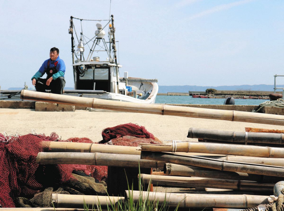 海底清掃で拾い上げたごみを前に、漁の再開を待ち望む漁師＝石川県七尾市石崎町で