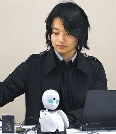 松江市内から三好史子さんが遠隔操作した分身ロボット「オリヒメ」と、説明をする開発者の吉藤健太朗さん＝１８日、東京・永田町で