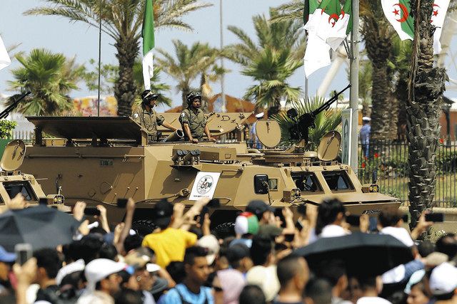 独立60周年の軍事パレードで、大通りを進む戦車を眺める市民ら＝﻿5日、アルジェで（AP）
