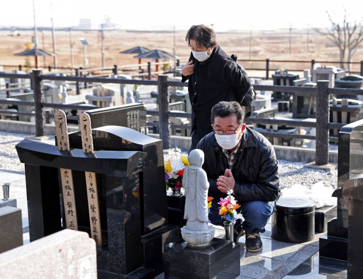 母ヒデヨさん（奥）と請戸地区にある高台の墓地を訪れた会社員の柴野正男さん（６４）。津波で妻広子さんを亡くした。「頑張ってやってるよ」と墓に手を合わせた。今は避難先の福島県郡山市で暮らす。毎年この日は「どうして助かってくれなかったのか」と妻を思い出すという＝２０２２年３月１１日、福島県浪江町で（沢田将人撮影）