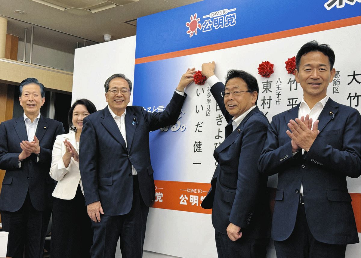 当選確実が報じられた候補者の名前にバラの花を付ける斉藤鉄夫代表（中）