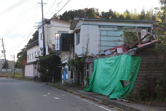 双葉駅近くは震災後１０年半が過ぎても、崩れかけた家やビニールシートで入り口が塞がれた店が並ぶ＝福島県双葉町で