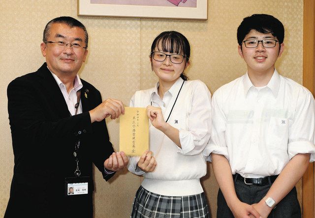 吉田市長（左）に寄付金を渡す本庄東高校の野辺さん（中）と磯田さん＝本庄市役所で
