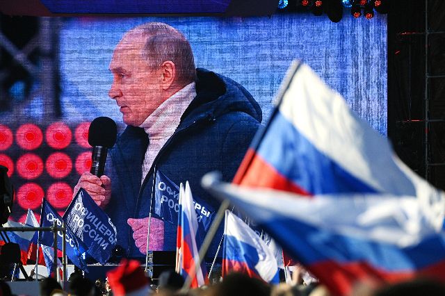 今年3月、クリミア併合8周年のイベントで。巨大なスクリーンに映し出されたプーチン大統領＝AP
