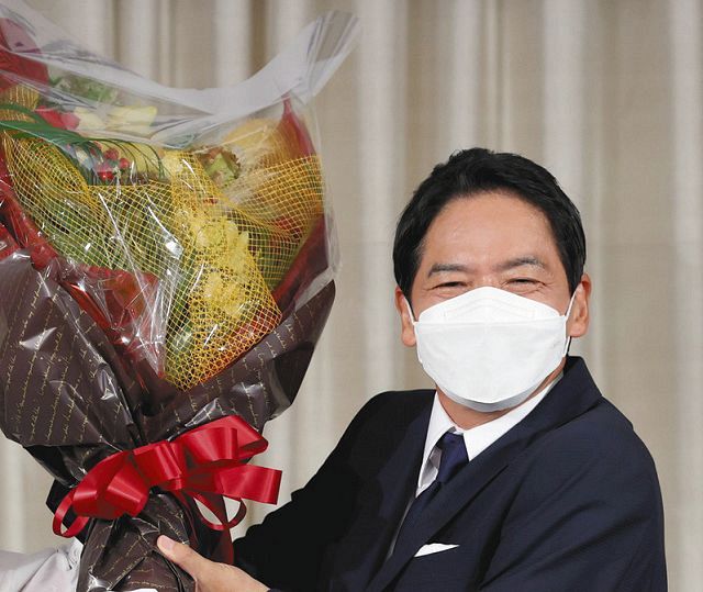 初当選を確実にし、花束を手に笑顔を見せる山中竹春氏＝２２日午後８時４分、横浜市中区で