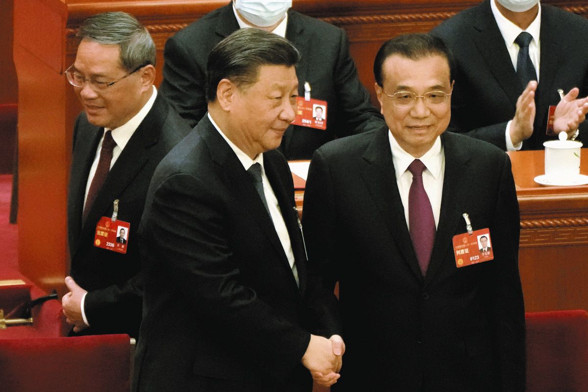 3月11日、北京の人民大会堂で、首相として最後の全人代を終えて習近平国家主席と握手する李克強氏（右）。後ろは新たに首相に就いた李強氏＝AP
