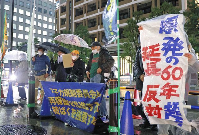 原子力規制委員会が入るビルの前で原発の運転期間延長などに抗議する人たち＝１３日、東京都港区で