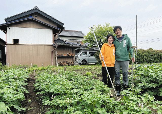 移住した藤田さん夫妻。母屋前の畑に収穫目前のジャガイモの葉が広がる＝栃木市で
