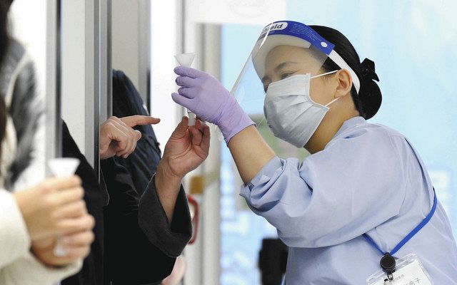 海外から到着した乗客が採取した唾液を確認する検疫担当者＝2020年12月27日、成田空港で