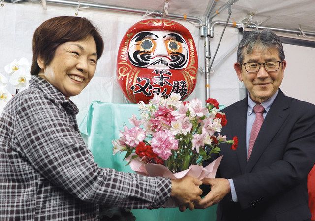 初当選し、妻の幸子さん（左）から花を受け取る橋本弘山さん＝羽村市で
