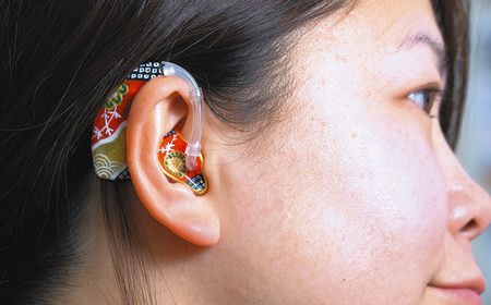 装飾された補聴器をつける松島亜希さん＝いずれも東京都福生市で