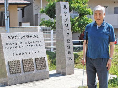 「点字ブロック発祥の地」の石碑を紹介する竹内昌彦さん＝岡山市で