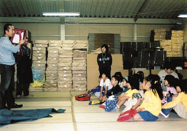 2000年ごろ、社会科見学で子どもたちに説明する土屋成範社長（左）＝土屋鞄製造所提供