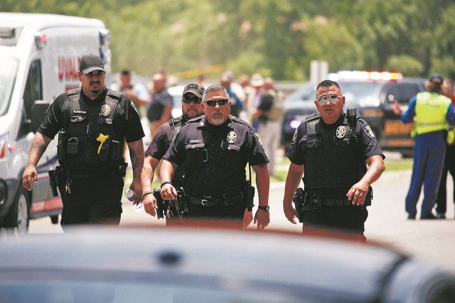 ﻿24日、銃乱射事件が起きた米南部テキサス州ユバルディの小学校近くを歩く警察官＝AP
