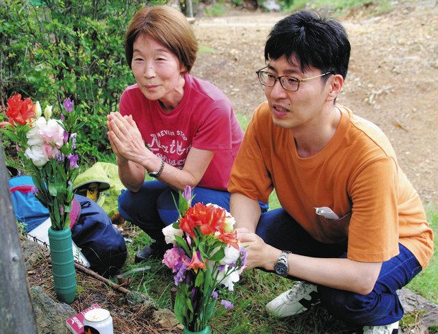 【当時は母のおなかの中　小沢さん親子が報告】小沢孝之さんの墓標に手を合わせる長男の秀明さん（右）と、妻紀美さん＝いずれも上野村で 