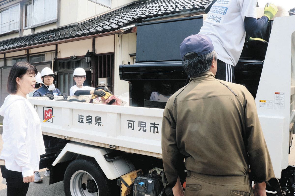 被災家屋から運び出されトラックの荷台に載せられたピアノを見守る細川里美さん（左）＝13日、石川県珠洲市正院町小路で