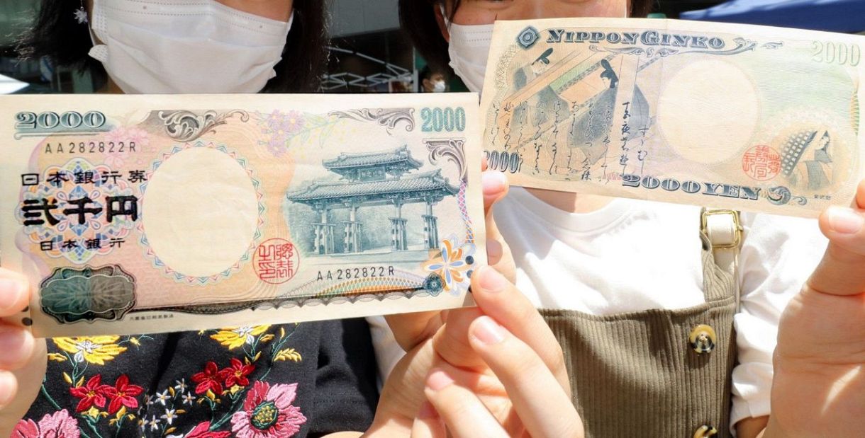 2000円札。首里城の守礼門が印刷された表面㊧と源氏物語絵巻の一部などが印刷された裏面㊨