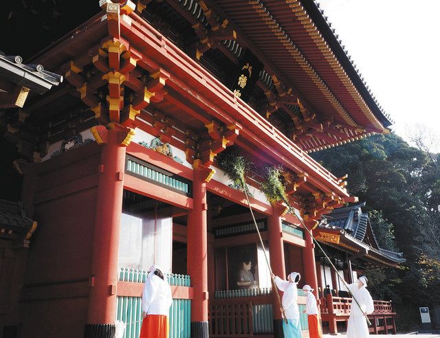 すす竹やはたきで楼門を掃除する鶴岡八幡宮の神職とみこ＝鎌倉市で
