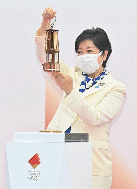 東京五輪の聖火が開催地の東京都に入り、お披露目式で聖火を納めたランタンを掲げる小池知事