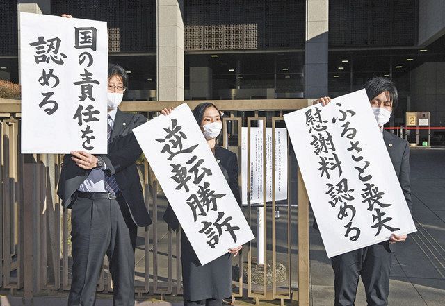 原発避難者訴訟の控訴審判決で勝訴し、垂れ幕を掲げる原告代理人の弁護士ら＝19日、東京・霞が関の東京高裁前で