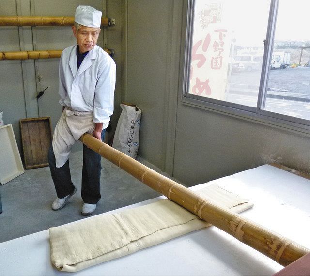 太い青竹に体重をかけ、移動しながら小麦粉を伸ばしていく佐野らーめんの伝統技法「青竹打ち」（佐野市提供）