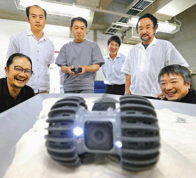 月面探査ロボを操作する中島紳一郎さん（左から３人目）を囲むプロジェクトチームのメンバーたち。開発に加え、資金調達やＰＲ活動などを協力して行っている＝東京都大田区で
