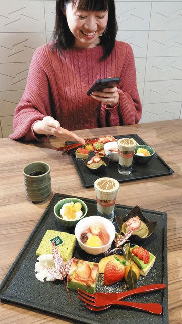 繊細に盛り付けられたデザートプレートを前に、うれしそうに写真を撮る女性＝東京都千代田区のレストラン１８９９お茶の水で