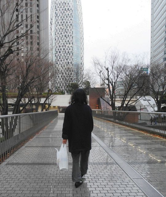 食品配布で受け取った袋を手に、会場を後にする女性＝東京・新宿区で