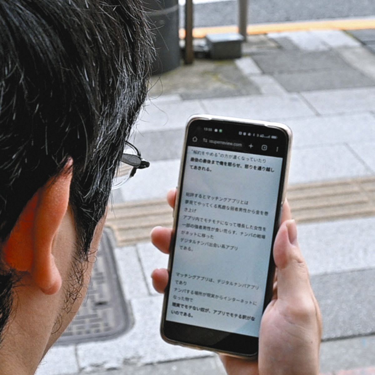 自身の経験を書いたブログを見つめるトモイナさん＝東京都港区で