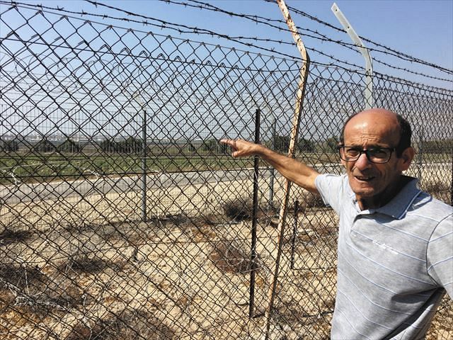 ７月末、イスラエル南部で、フェンス越しに見える約８００メートル先のガザを指すラハミムさん