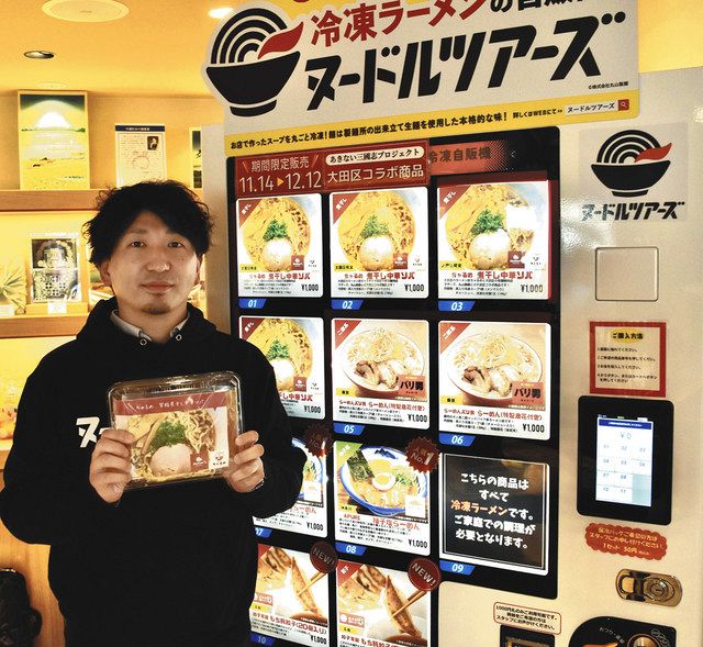 期間限定で設置された冷凍ラーメン自販機を紹介する丸山晃司さん＝京急蒲田駅で
