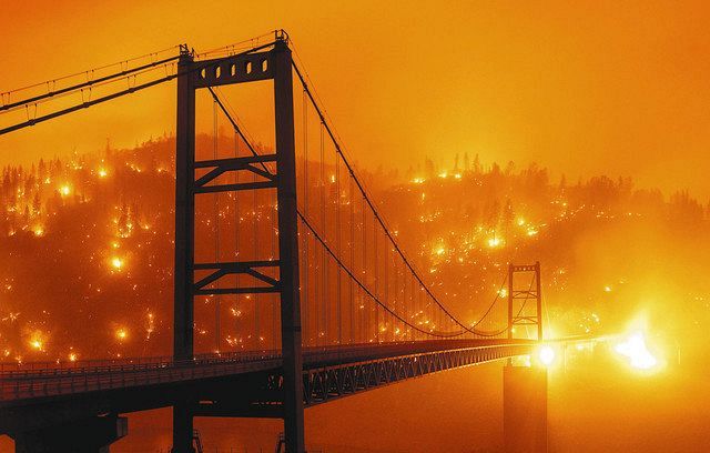 ９日、橋後方の丘で燃え広がる炎＝米カリフォルニア州（ＡＰ＝共同）