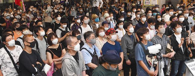 マスク姿で都知事選候補者の街頭演説を聞く有権者ら＝２８日、東京都内で