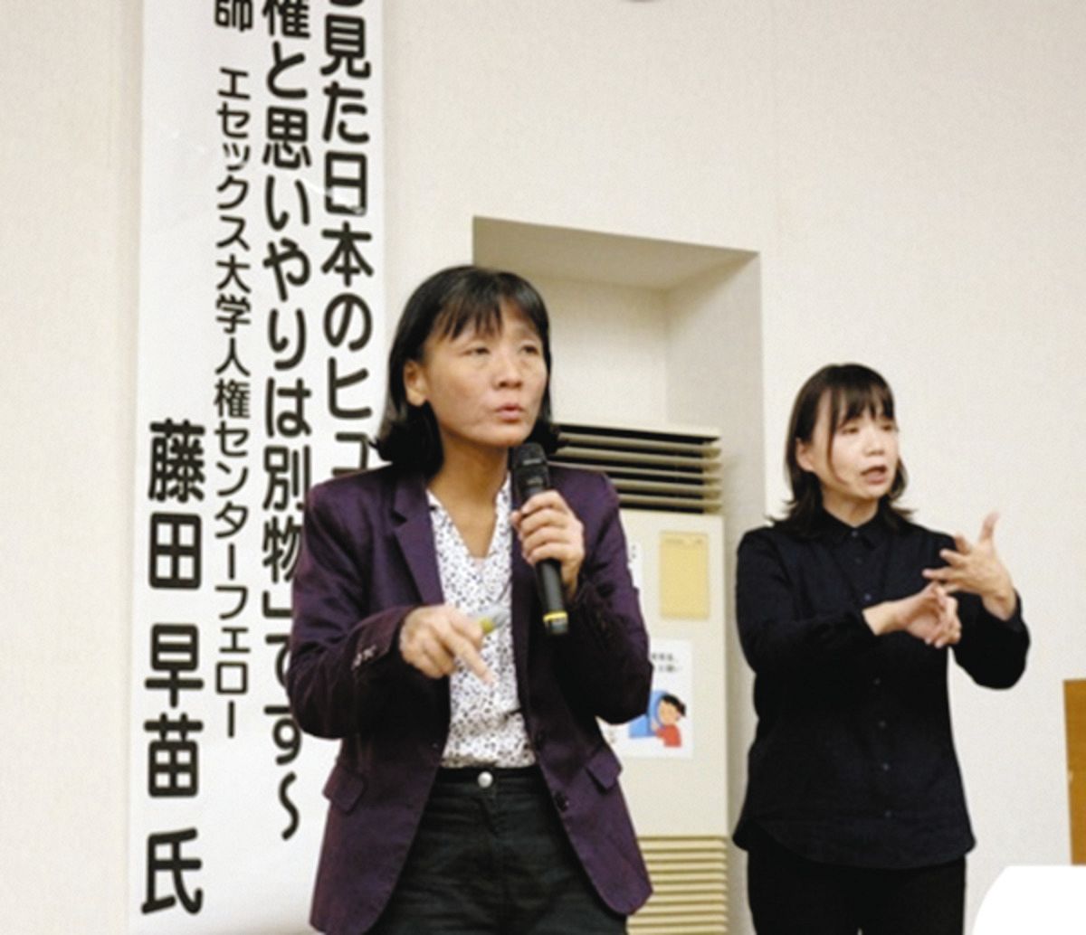 人権問題について講演する藤田早苗さん（左）。右は手話通訳者＝2023年11月、大分県中津市で（藤田さん提供）