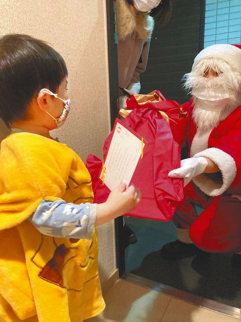 サンタクロースの格好をしたボランティアから絵本を受け取る子ども＝２０２０年１２月、ＮＰＯ法人チャリティーサンタ提供