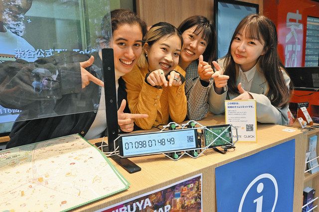 観光案内所「シブハチボックス」の受付に置かれた気候時計を指さすa(n)actionのメンバーたち＝15日、東京都渋谷区で