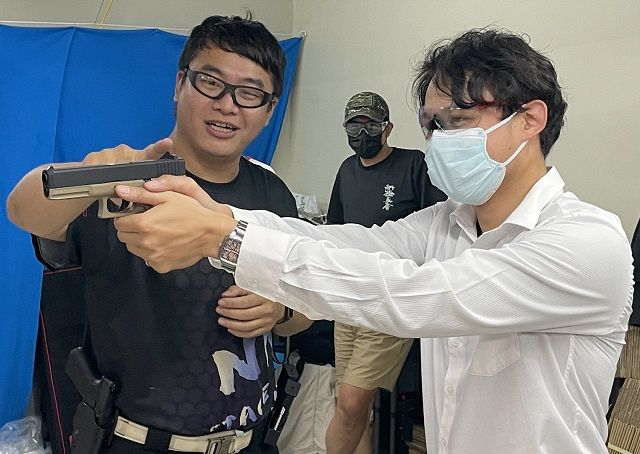 クラブのメンバーに射撃技術を教える潘昭戎隊長（左）＝24日、台北市のNH倶楽部で、石井宏樹撮影