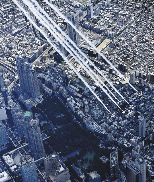 東京都庁（左）上空を飛行するブルーインパルス＝５月２９日、東京都新宿区で